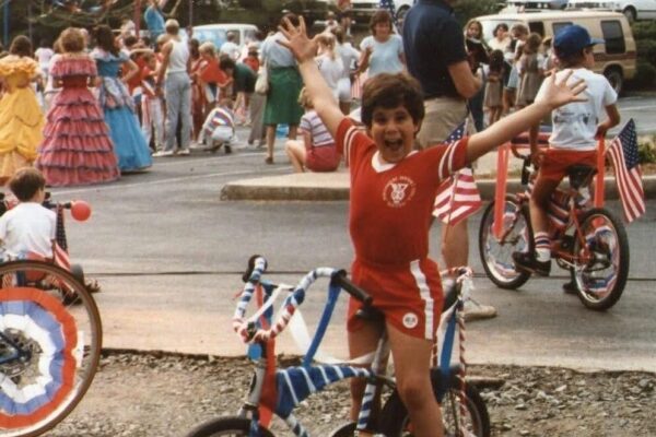 older photo from the 70s of boy on bike with hands in air at the Dunwoody 4th of July parade