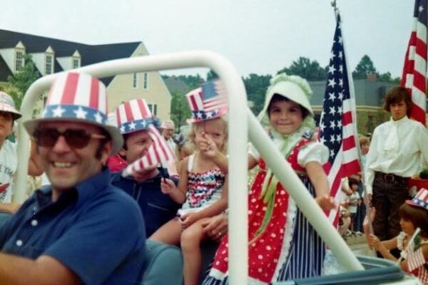 older photo from the 70s of a man driving kids in back of Jeep at Dunwoody 4th of July parade